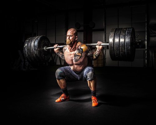 Person learning how to do a barbell squat with an instructor